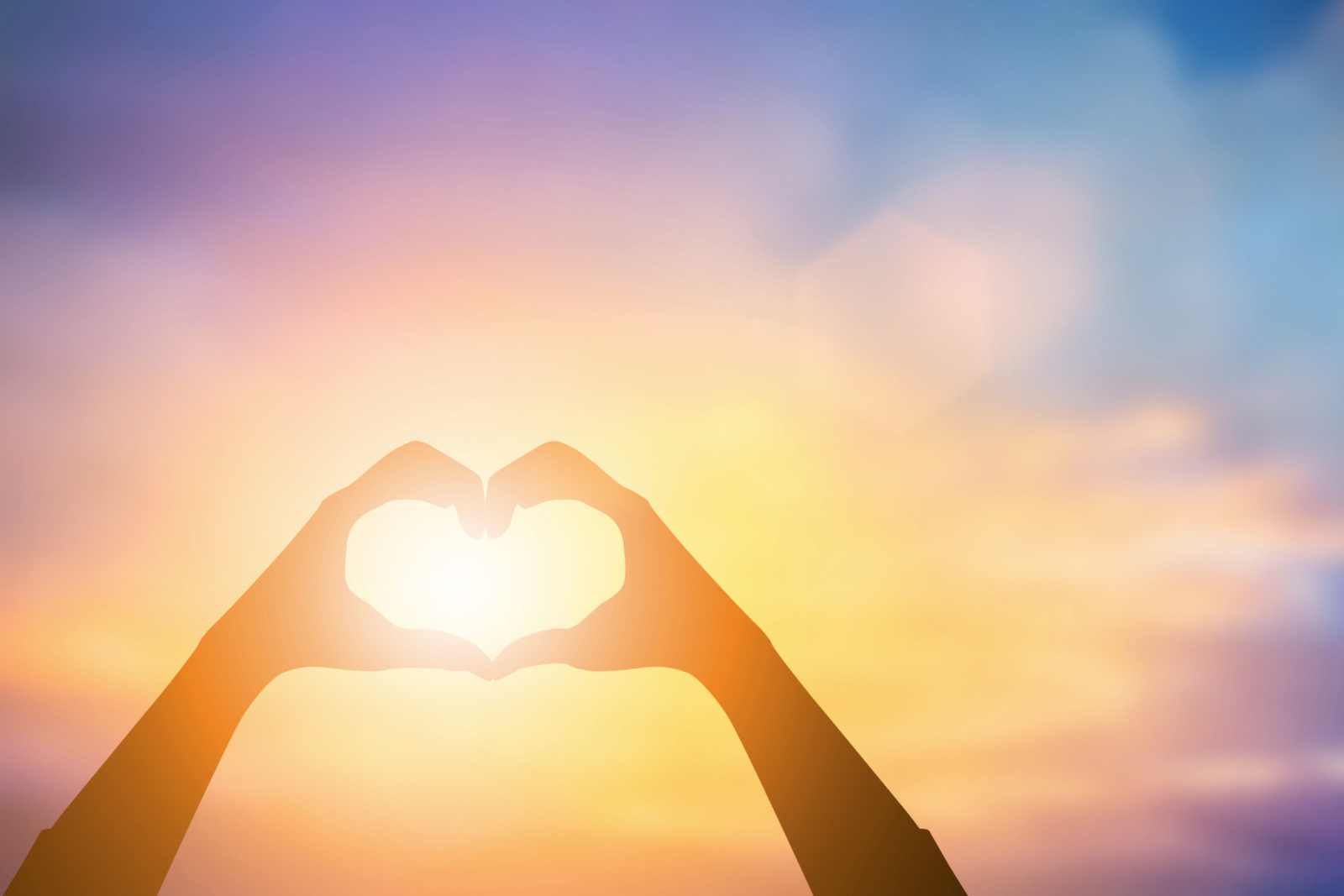 Hands forming a heart shape against the rising sun. Hands forming heart shape against sun.